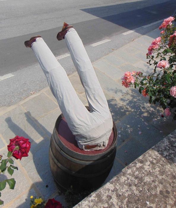 Decoration with the man upside down in wine barrel among the red and pink flowers