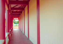 Outside view of the old house with red columns, and plants on background