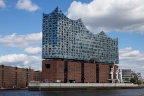 Shiny Elbe Philharmonic Hall on the coast of Elbe in Hamburg, Germany, under the blue sky with clouds