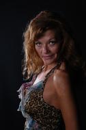 Portrait of the woman, in colorful dress, with the necklace, in light, at black background