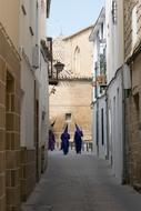 people in traditional costumes on a narrow street of the old town