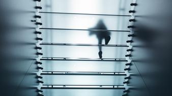 Silhouette of the person walking on the glass stairs in light