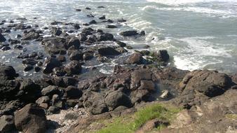 black rocks on the beach in the water