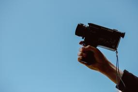 camera in hand against a clear blue sky