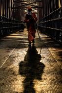 People, walking on the shiny bridge in light, with the shadow