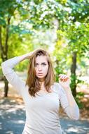 Portrait of the posing girl on the path, among the colorful and beautiful trees, in the beautiful park