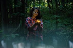 girl with a fiery flower in the dark of a wild forest