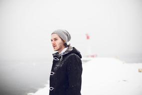 young caucasian man on coast at snowy winter