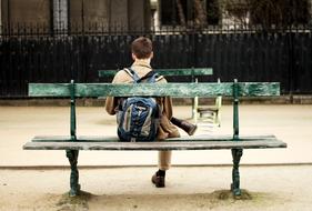 young Man with backpack sits on bench