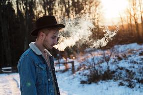 Guy breathing out smoke at winter evening