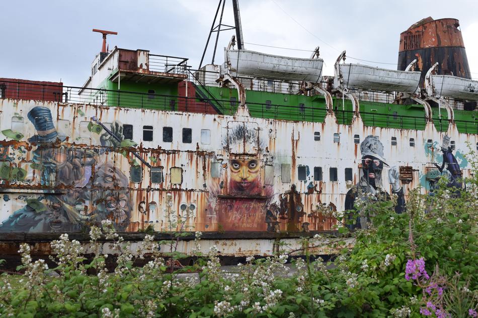 Old 'Duke of Lancaster' ship with colorful graffities, among the plants