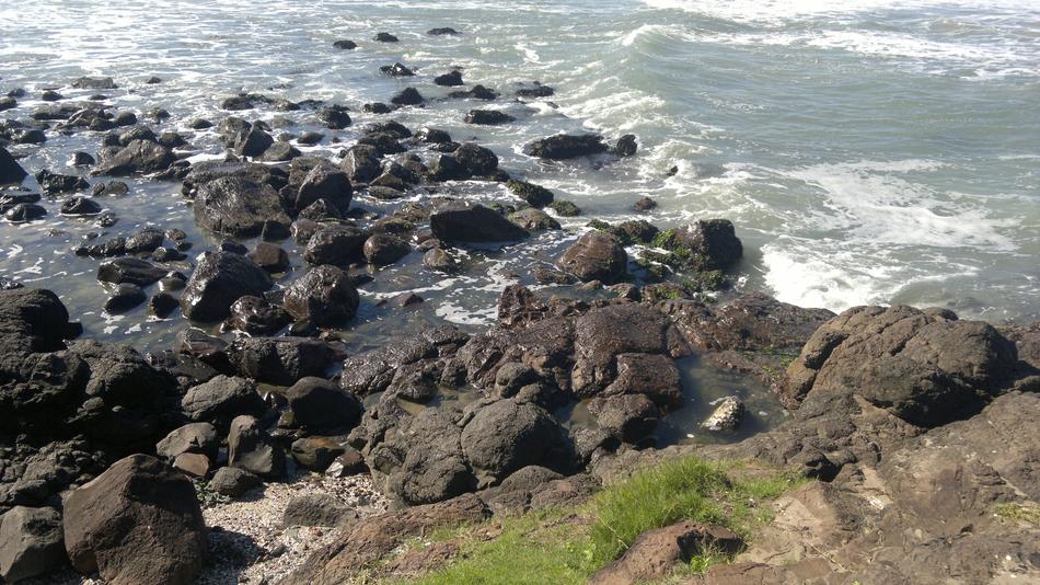 black rocks on the beach in the water