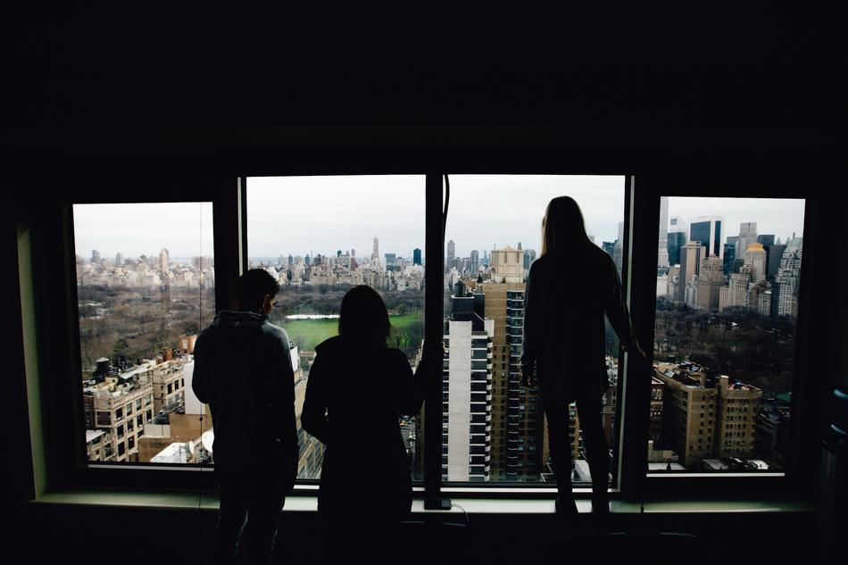 silhouettes of friends looking at the city from the window