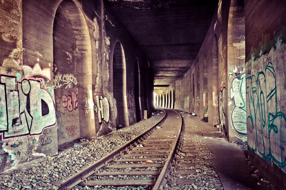 Interior of the old tunnel with railroad track, among the walls with graffities