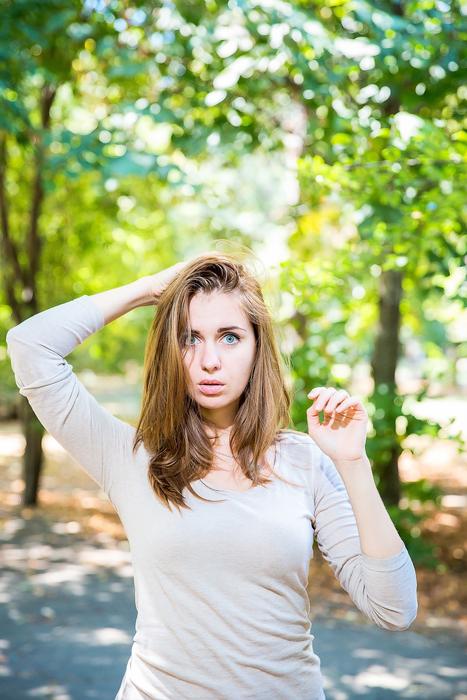 Portrait of the posing girl on the path, among the colorful and beautiful trees, in the beautiful park