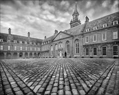 Black and white photo of the old building with court yard, under the sky with clouds