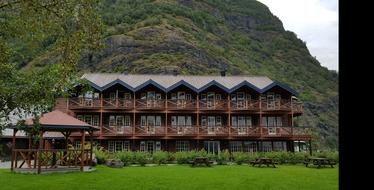 Beautiful landscape of the wooden building among the green plants, near the mountain in Norway