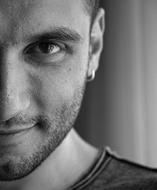 Black and white photo with the portrait of the half of the face of the bearded man, with earring