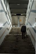 Person walking up on the stairs, among the shiny walls, at the railway station