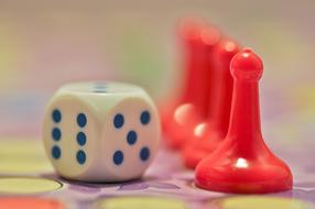 Close-up of the shiny, red figures and white and blue dice, on the colorful board