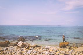 distant view of a fisherman on a rocky ocean coast