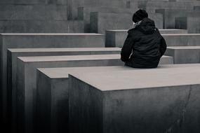 lonely guy sitting near a stone slab