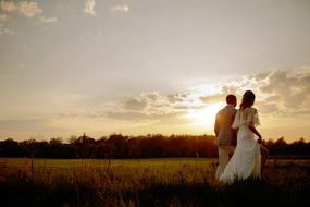 landscape of newlyweds walk in a rural meadow