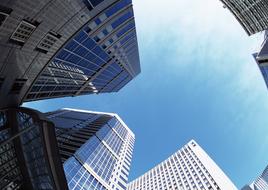 Low angle shot of the shiny buildings with windows in the city, under the blue sky with white clouds