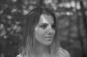 Black and white portrait of the girl, in shadow and light, among the trees