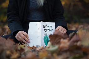 girl with an open book in an autumn park in a blurry background