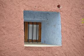 grated Window in pink stone wall