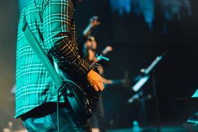 man with a guitar on stage, view from the back