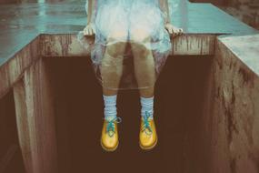 Girl with yellow and turquoise shoes, sitting on the construction