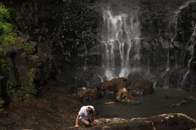 young man climbing rock at scenic waterfall