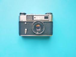 Close-up of the shiny, antique camera on the turquoise surface in light