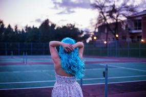 girl with blue hair near the tennis court at dusk