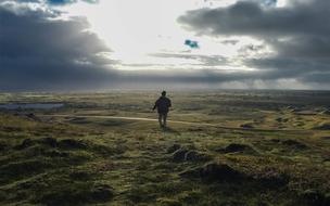 man walking on grass and Dark Clouds on Sky