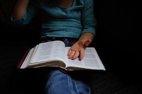 Kid, reading a book, while sitting, among the darkness