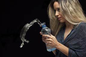 blonde woman with bottle of water on black background