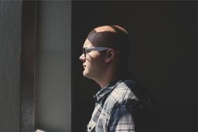 Profile portrait of the bald man with eyeglasses, in light