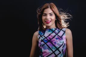 Smiling woman in colorful dress with pattern, at black background