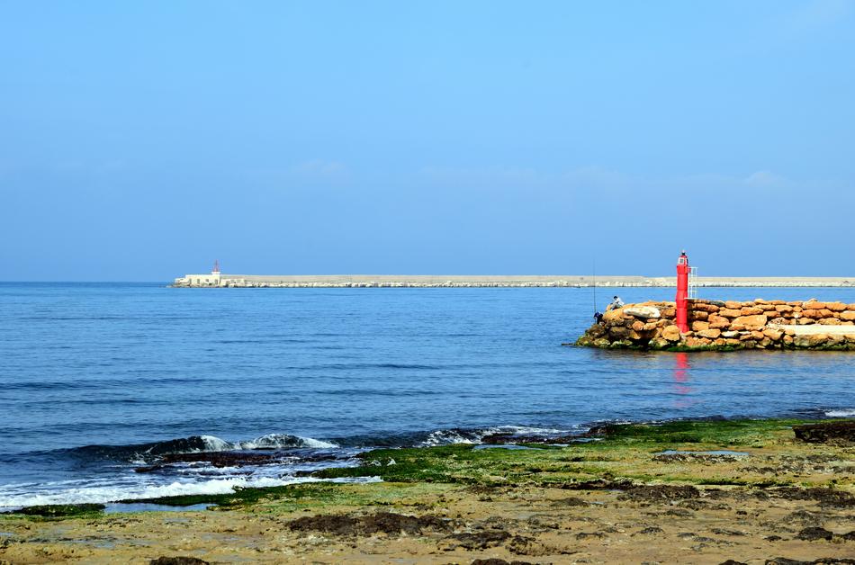 red lighthouse on an island in the sea