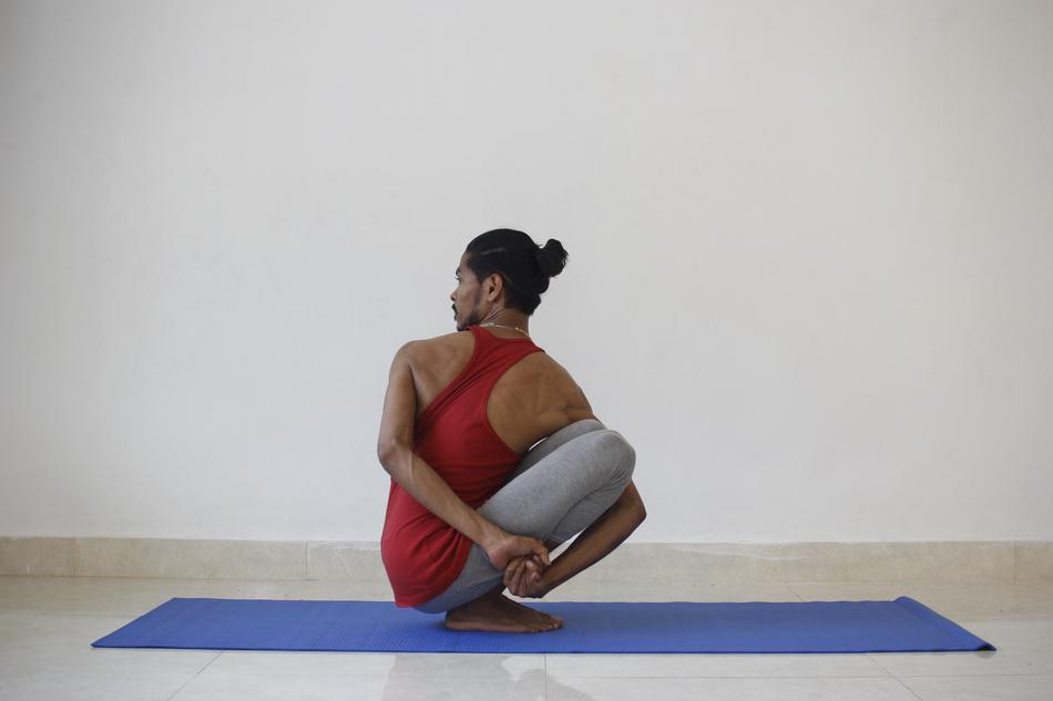 Bearded Yogi, practicing yoga on the mat, near the wall