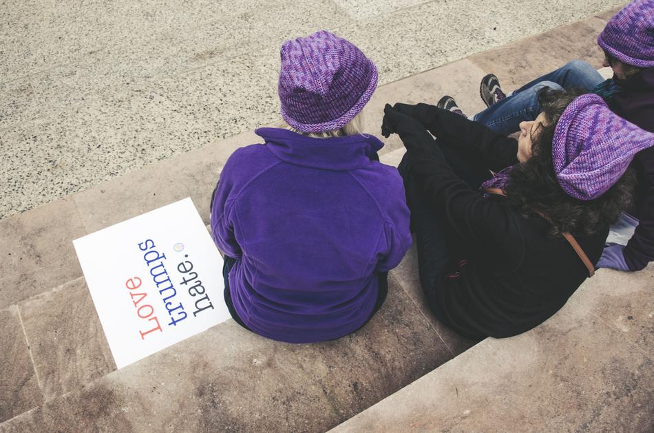 Women Sitting love trumps hate text