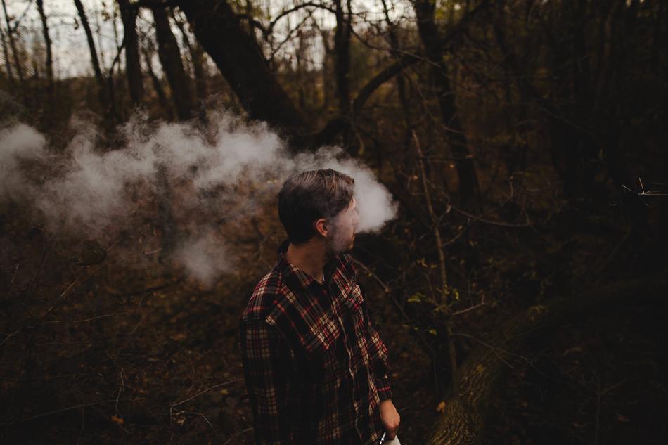 a man with steam coming out of his mouth in the woods.