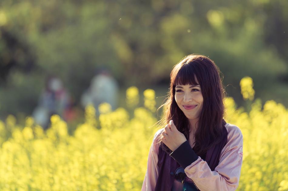 photo of a brunette with long hair on a blooming yellow field