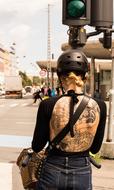 Girl with tattoo on back riding Bike in city