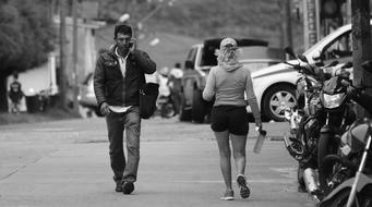 Black and white photo with the Columbian people, walking on the road near the vehicles