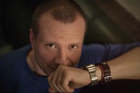 Portrait of the man, with the wrist watch and bracelet, among the darkness