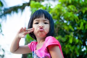 little girl in a pink t-shirt posing on a blurred background